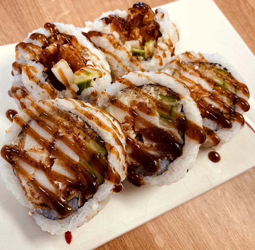 Chicken teriyaki sushi roll drizzled with teriyaki sauce on a white plate at Hana Sushi, Winnipeg